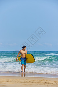 年轻男士拿着冲浪板海边行走图片