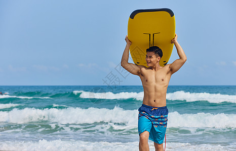年轻男士举着冲浪板走向岸边图片