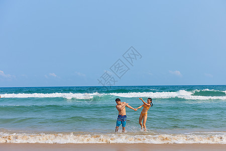 海岛旅游的男孩年轻情侣海边戏水打闹背景