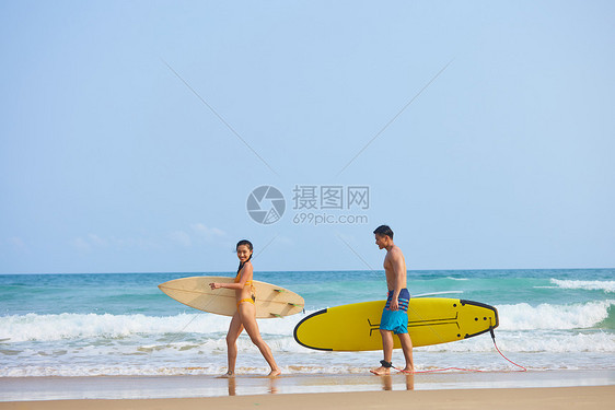 青年男女拿着冲浪板海边聊天图片