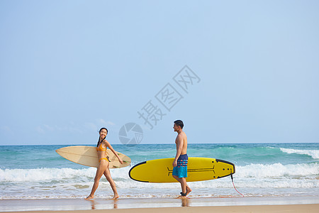 男女性感青年男女拿着冲浪板海边行走背景