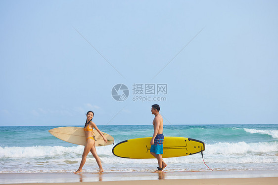 青年男女拿着冲浪板海边行走图片