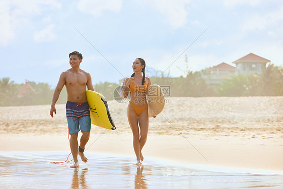 青年男女拿着冲浪板海边行走图片