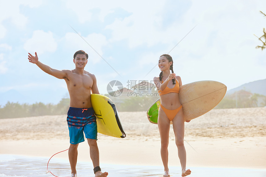 青年男女拿着冲浪板海边行走图片