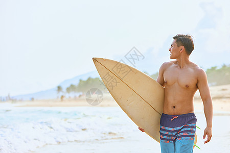 夏日海滩年轻男士拿着冲浪板海边行走背景