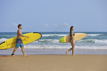 夏日海滩年轻男女拿着冲浪板海边行走背景