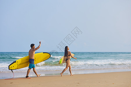 海滩背影年轻男女拿着冲浪板海边行走背影背景