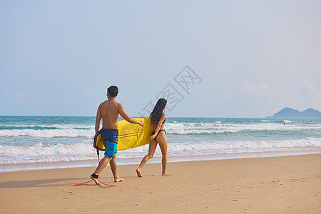 夏日海滩青年男女拿着冲浪板海边行走背景