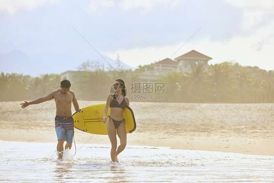 青年男女拿着冲浪板海边行走图片