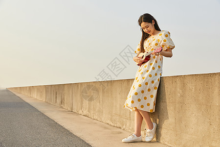 夏日美女在马路边抱着尤克里里的悠闲女性背景