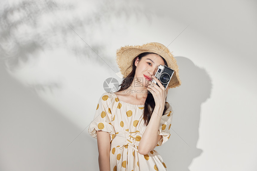 手持相机拍照的夏日度假美女图片