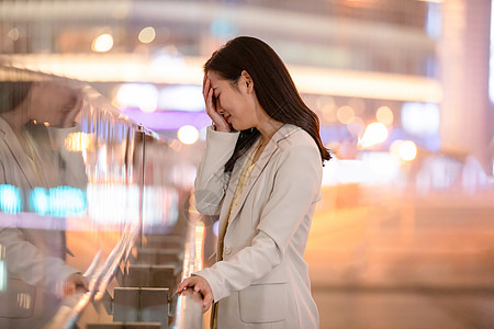 城市里捂脸伤心难过的女性背景图片