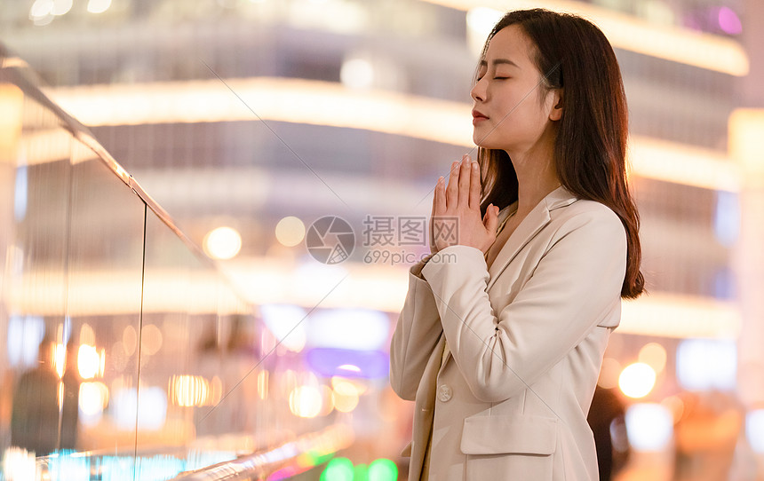 城市里双手合十祈祷的女性