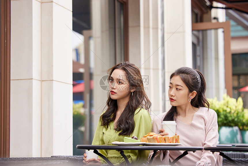 年轻闺蜜们在室外餐桌前一起喝饮料聊天图片