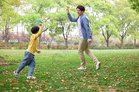 玩纸飞机得男孩父子公园里玩纸飞机背景