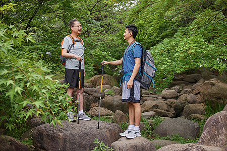 中年父子拿登山仗徒步郊游高清图片