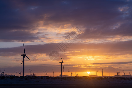 夕阳下的风力发电机剪影背景图片
