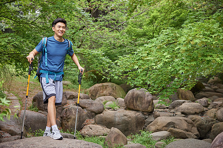 青年男性拿登山杖徒步高清图片