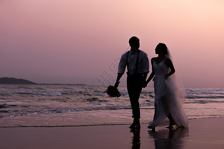 夫妇海边沙滩日落情侣散步剪影背景