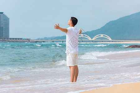 海岛旅游的男孩青年男性张开手臂拥抱大海背影背景