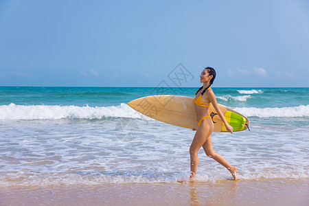 海边比基尼美女手拿冲浪板行走背景图片