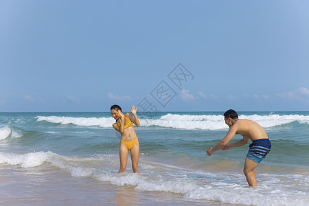 海边情侣年轻泳装情侣海边戏水打闹背景