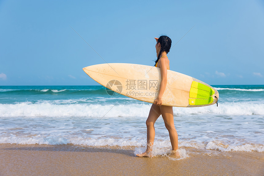 海边比基尼美女手拿冲浪板行走图片