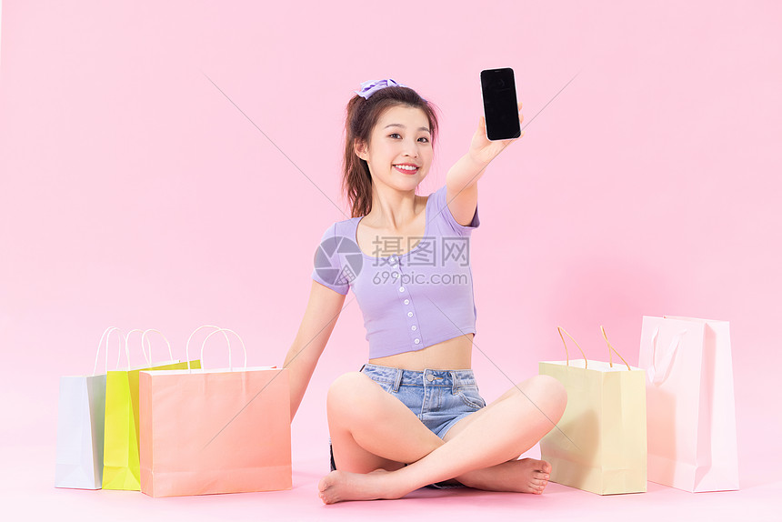 坐在购物袋旁的美女展示手机图片