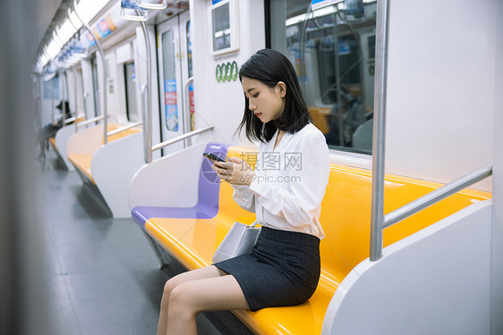 地铁上看手机的女性图片