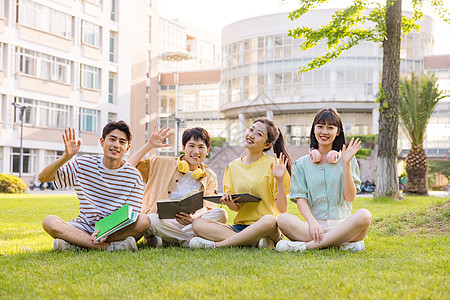 年轻大学生坐在草坪上打招呼图片