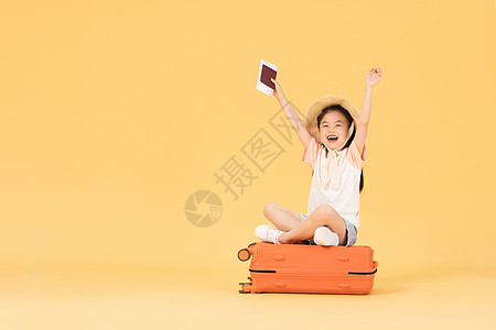 坐在行李箱上拿着机票和护照的小女孩图片