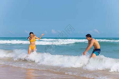 海边情侣年轻泳装情侣海边戏水打闹背景