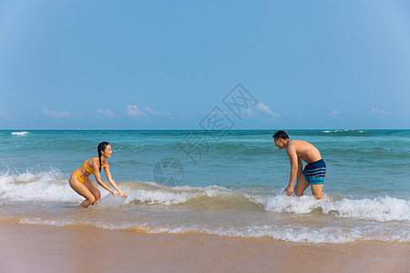 海边情侣年轻泳装情侣海边戏水打闹背景