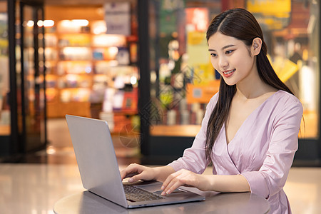 女性在商场休闲办公看笔记本电脑图片