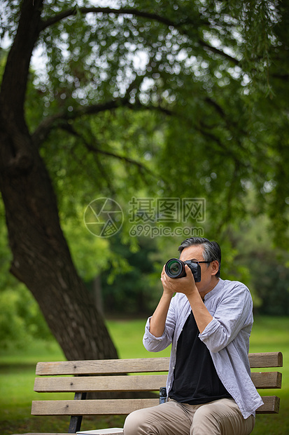 中年人使用相机拍摄户外风景图片