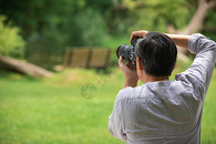 中年人使用相机拍摄风景背影图片