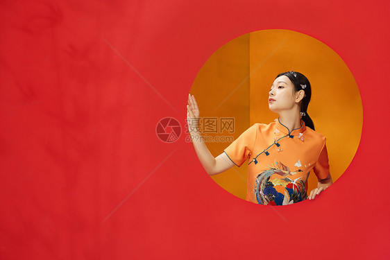 红色背景后的古典东方旗袍美女图片