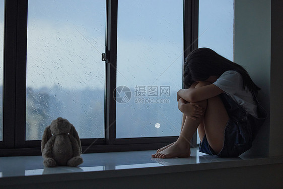 蜷缩在窗边哭泣的女孩图片