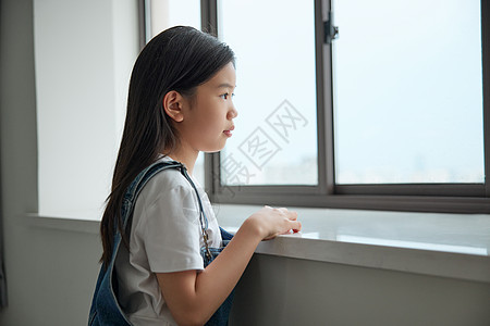 趴在窗前表情难过眺望远方的小女孩图片