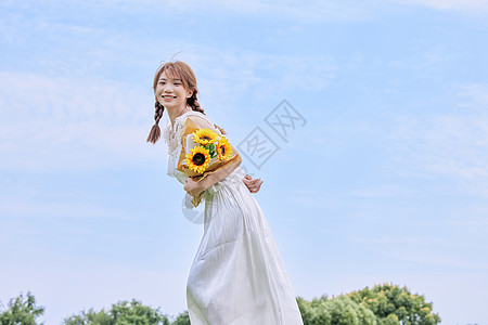 手拿鲜花夏日美女手拿向日葵背景