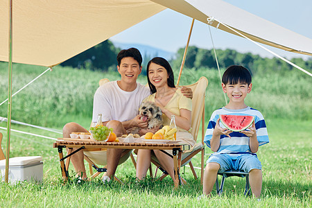 狗与西瓜夏天幸福一家人带着宠物户外露营背景