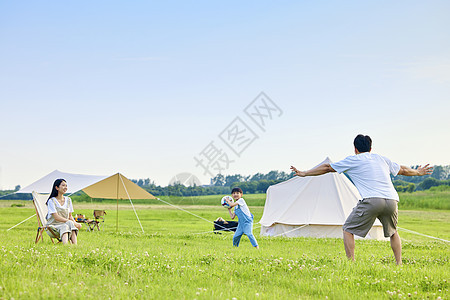 爸爸带着孩子草坪踢足球背景图片