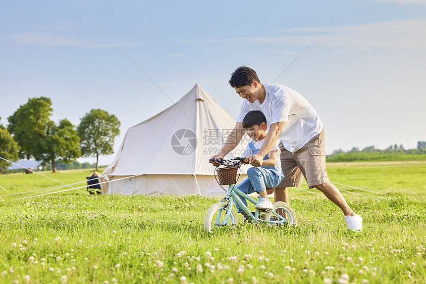 年轻爸爸陪伴小男孩学骑自行车图片