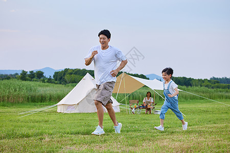 追跑打闹小男孩和爸爸在草坪上追逐打闹背景