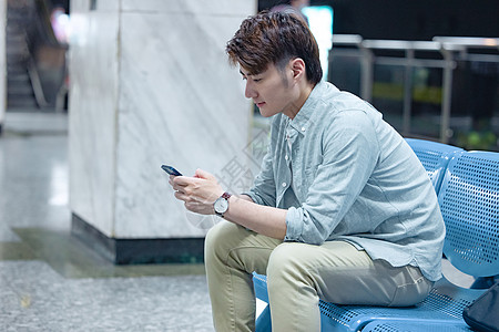 年轻男性坐在地铁站看手机图片