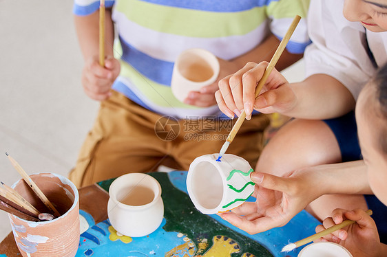 艺术老师教小朋友陶罐作画图片
