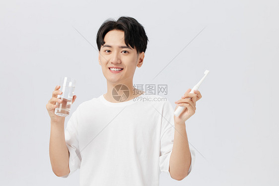 年轻男性手拿水杯刷牙图片
