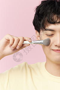 韩系男生手拿化妆刷闭眼特写图片
