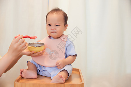 年轻宝妈喂食宝宝吃果泥高清图片