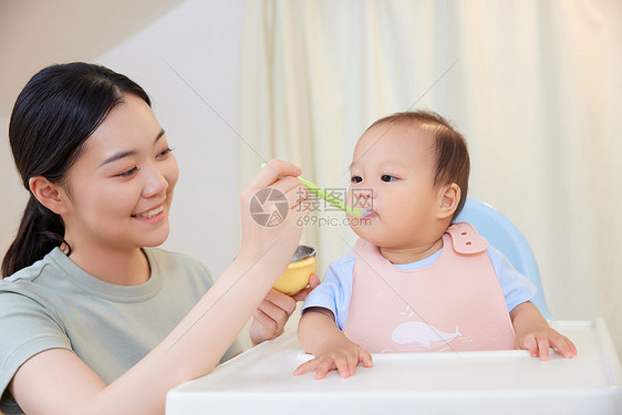 年轻宝妈喂食宝宝吃果泥图片